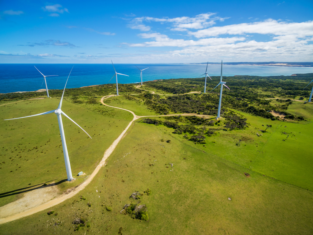 Wind turbines standing tall in a lush green field, harnessing renewable energy from the wind.