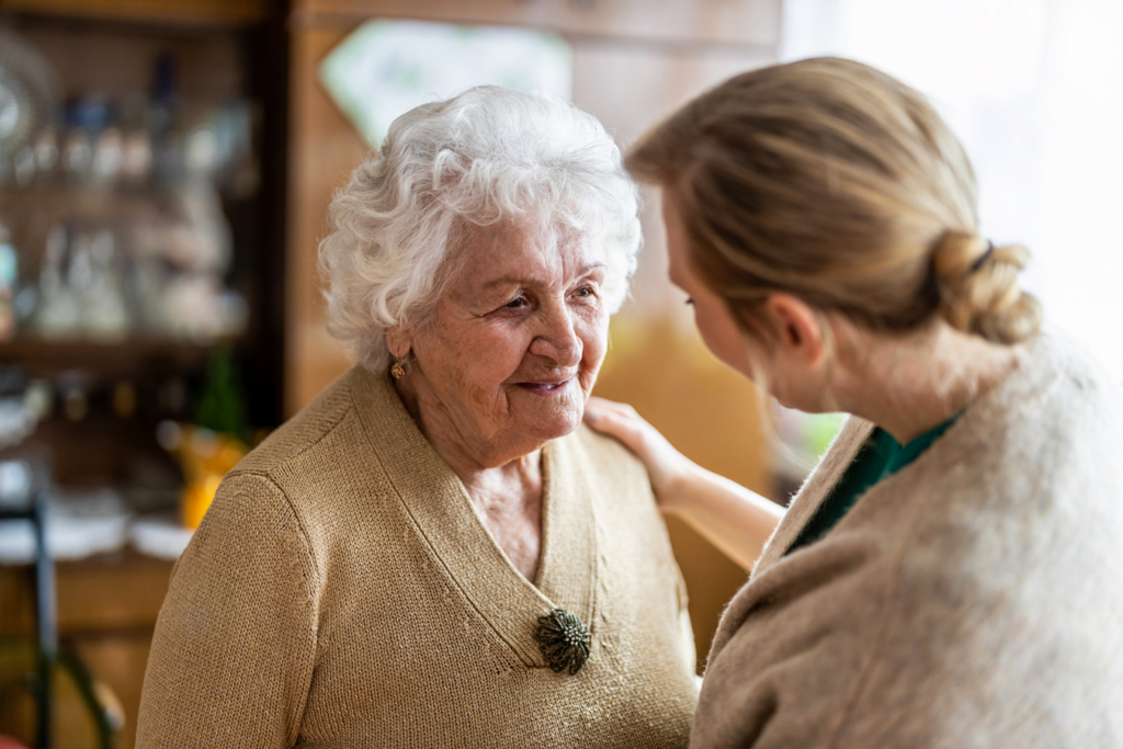 A younger woman conversing with an elderly woman in a cozy home setting.