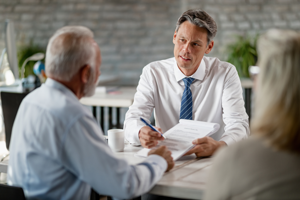 An individual in business attire having a discussion with two older adults.