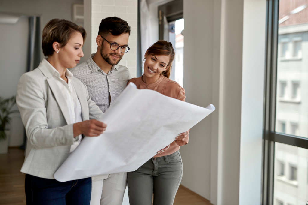 Three individuals examining a blueprint in an office setting.